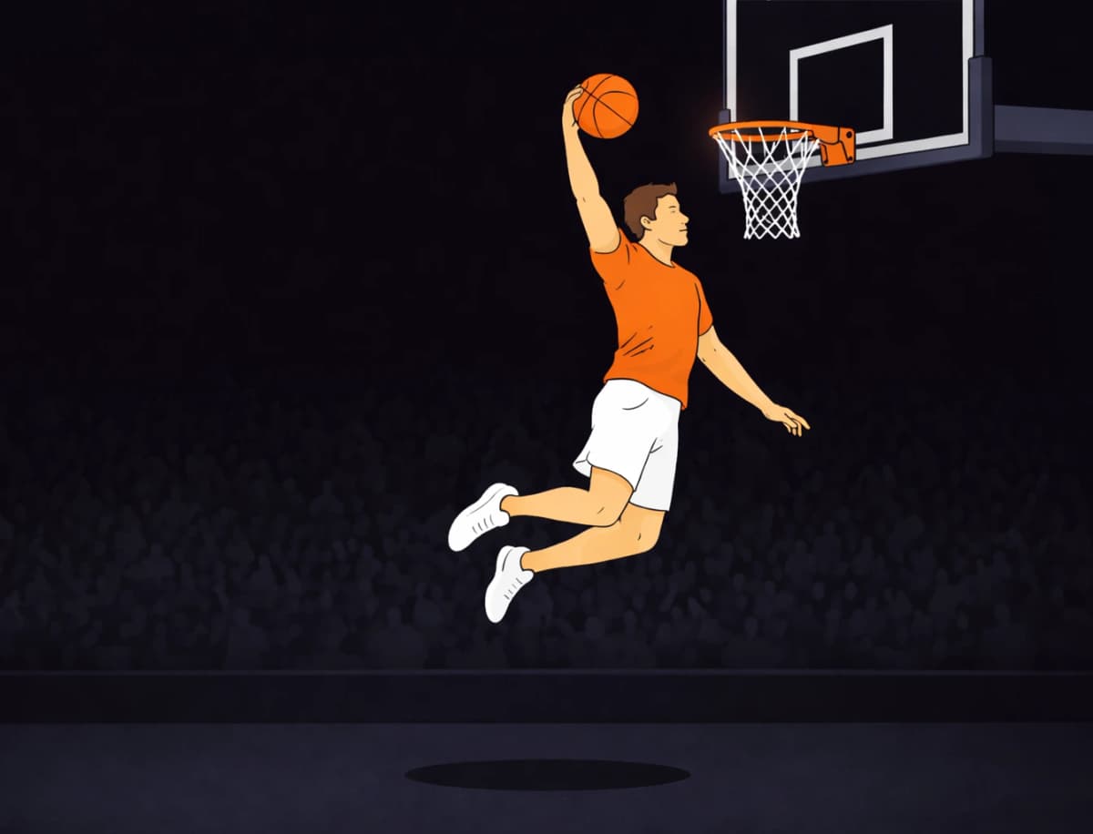 Athlete performing a high vertical jump to dunk a basketball infront of a crowd